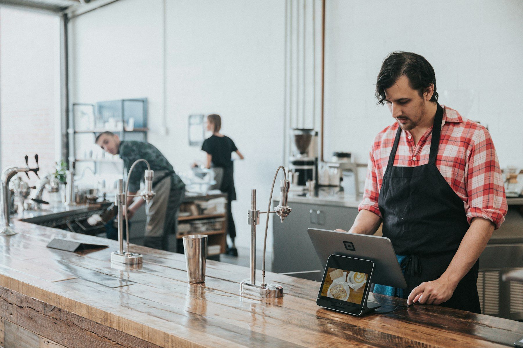 Responsable d’un coffee shop consultant ses chiffres sur ordinateur, au comptoir